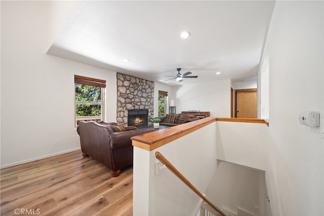 interior space with ceiling fan, hardwood / wood-style floors, and a stone fireplace