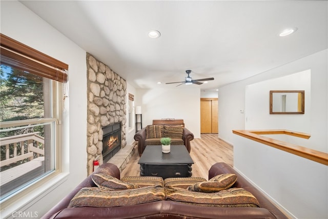 living room featuring light hardwood / wood-style floors, ceiling fan, and a fireplace