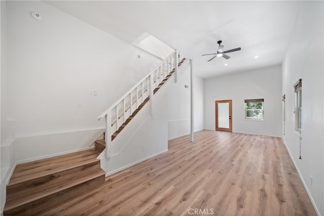 unfurnished living room with ceiling fan, light wood-type flooring, and vaulted ceiling