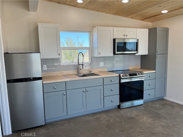 kitchen featuring white cabinets, lofted ceiling, appliances with stainless steel finishes, and tasteful backsplash