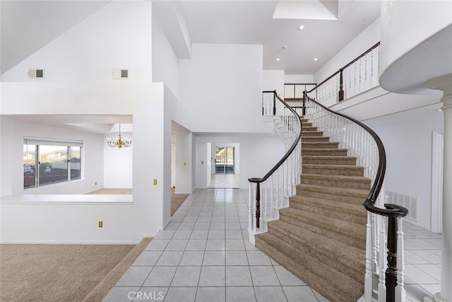 foyer entrance with light tile patterned flooring, a towering ceiling, and a notable chandelier