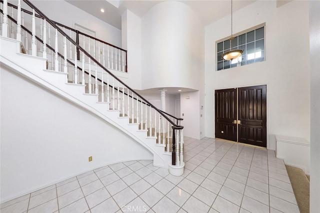 tiled foyer entrance featuring decorative columns and a high ceiling