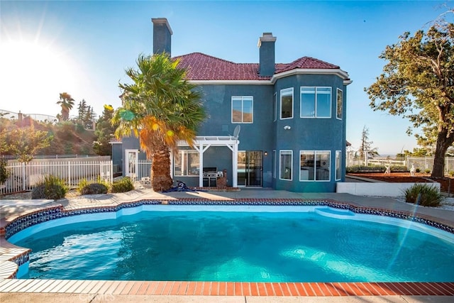 back of property with a fenced in pool and a pergola