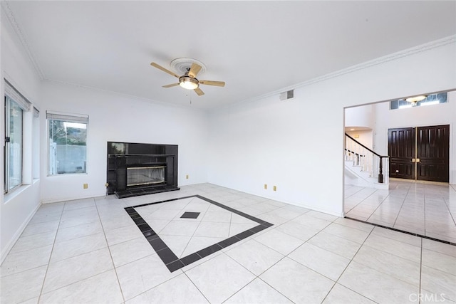 unfurnished living room featuring crown molding, ceiling fan, a tile fireplace, and light tile patterned floors