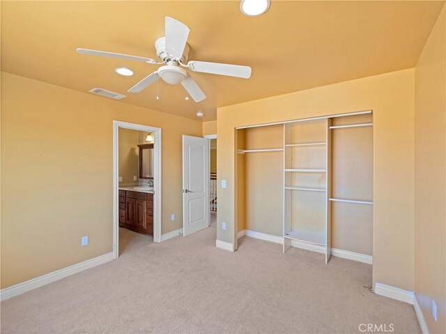 unfurnished bedroom featuring light carpet, sink, a closet, ceiling fan, and ensuite bathroom