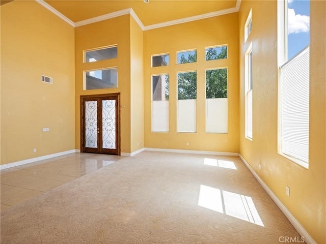 entryway with a high ceiling, light colored carpet, french doors, and crown molding