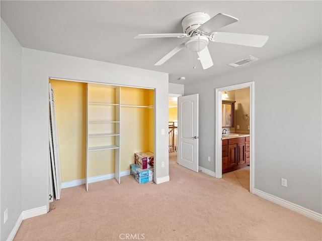 unfurnished bedroom with ensuite bathroom, light colored carpet, ceiling fan, sink, and a closet