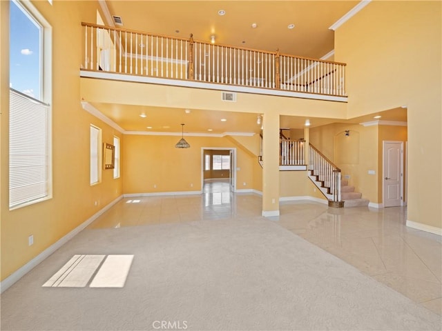 unfurnished living room with a wealth of natural light, crown molding, and a towering ceiling