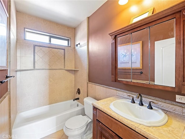 full bathroom with toilet, tiled shower / bath, tile patterned flooring, tile walls, and vanity