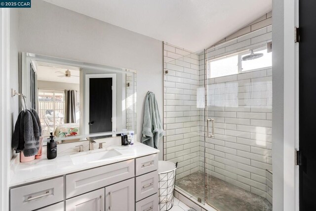 bathroom with lofted ceiling, ceiling fan, walk in shower, and vanity