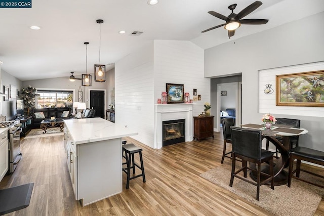 kitchen with pendant lighting, a breakfast bar, gas stove, lofted ceiling, and ceiling fan