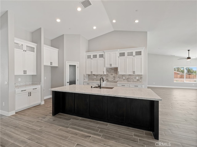 kitchen featuring an island with sink, light wood-type flooring, lofted ceiling, and ceiling fan