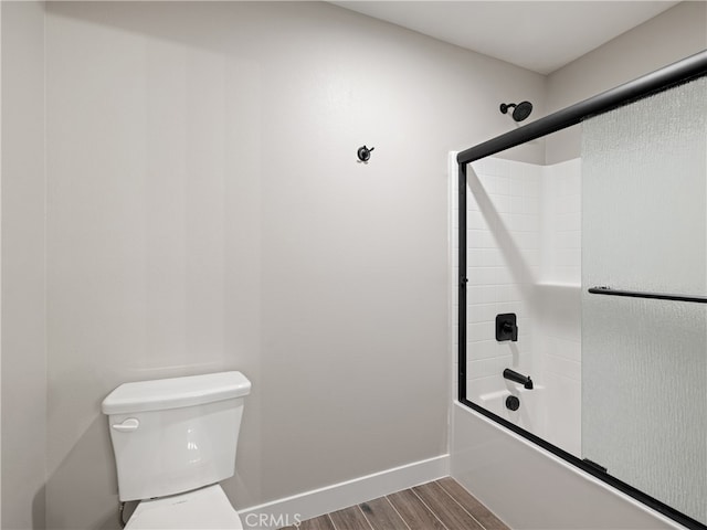 bathroom featuring hardwood / wood-style floors, shower / bath combination with glass door, and toilet