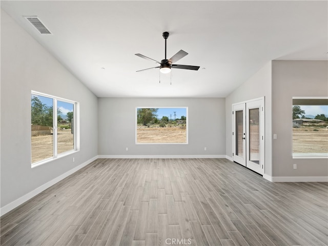 unfurnished living room featuring a healthy amount of sunlight, vaulted ceiling, ceiling fan, and light hardwood / wood-style flooring