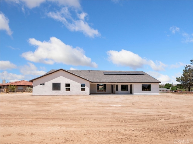 back of house featuring solar panels