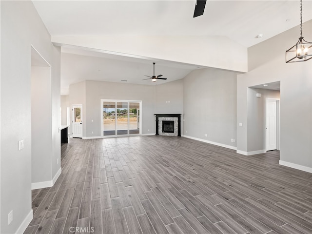 unfurnished living room with ceiling fan with notable chandelier, high vaulted ceiling, and dark hardwood / wood-style floors