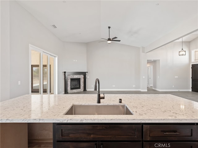 kitchen with lofted ceiling, ceiling fan, decorative light fixtures, dark brown cabinetry, and sink