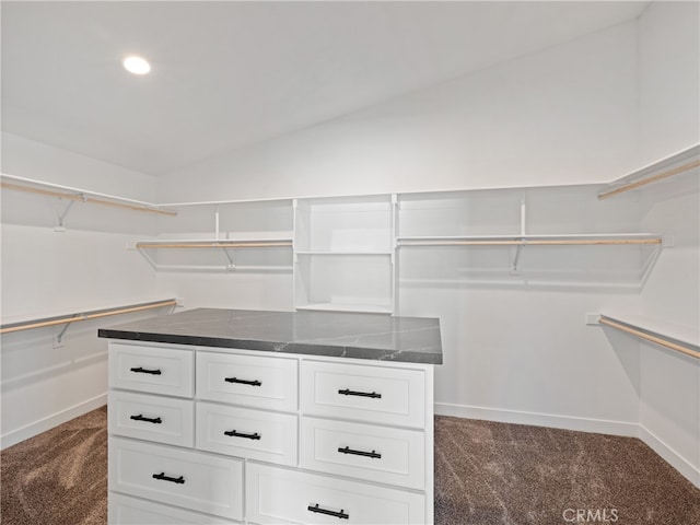 walk in closet with vaulted ceiling and dark colored carpet