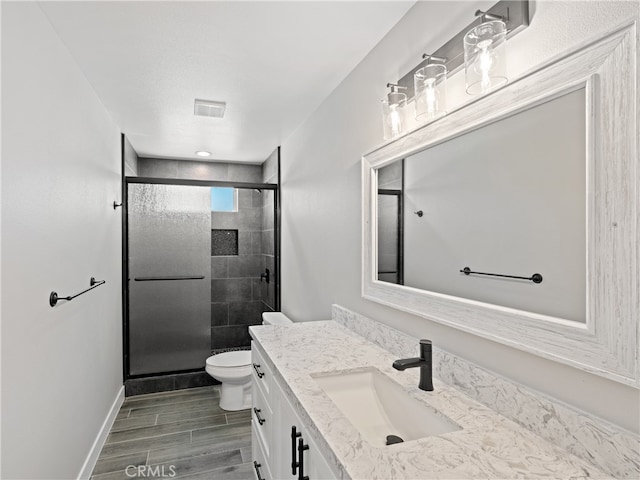 bathroom with an enclosed shower, vanity, and toilet