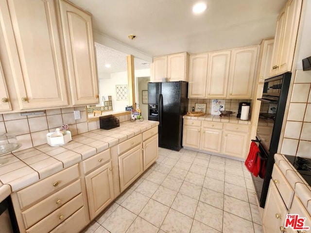 kitchen with tile countertops, black appliances, backsplash, and light tile patterned floors