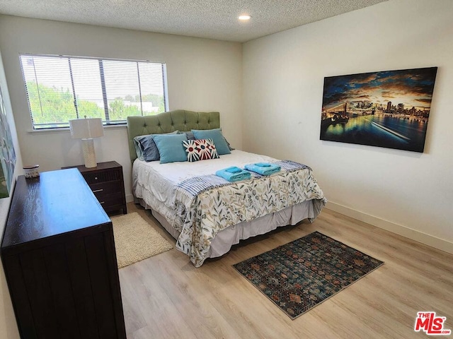 bedroom with light hardwood / wood-style flooring and a textured ceiling