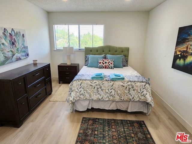 bedroom with a textured ceiling and light wood-type flooring