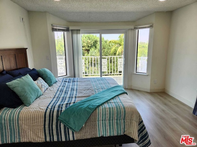 bedroom featuring light hardwood / wood-style flooring, a textured ceiling, and access to exterior