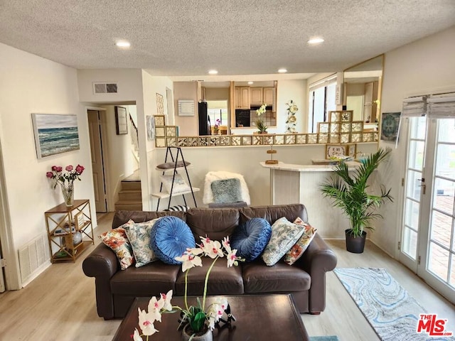 living room with a textured ceiling and light wood-type flooring