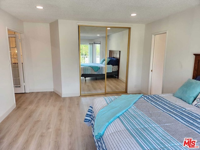 bedroom with a closet, a textured ceiling, and light wood-type flooring