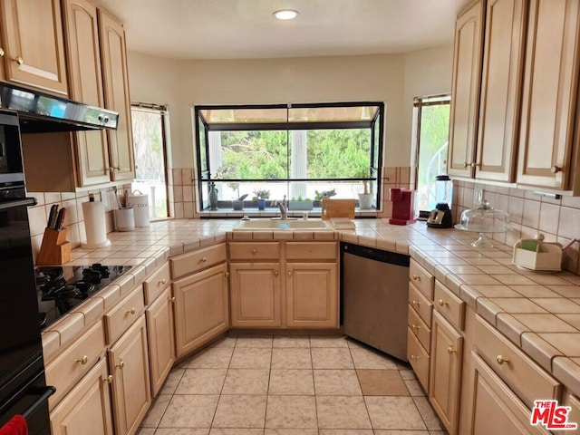 kitchen with tile countertops, backsplash, sink, black appliances, and light brown cabinetry