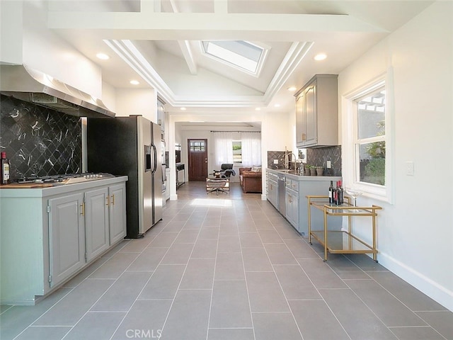 kitchen featuring light tile patterned floors, gray cabinets, appliances with stainless steel finishes, tasteful backsplash, and vaulted ceiling with skylight