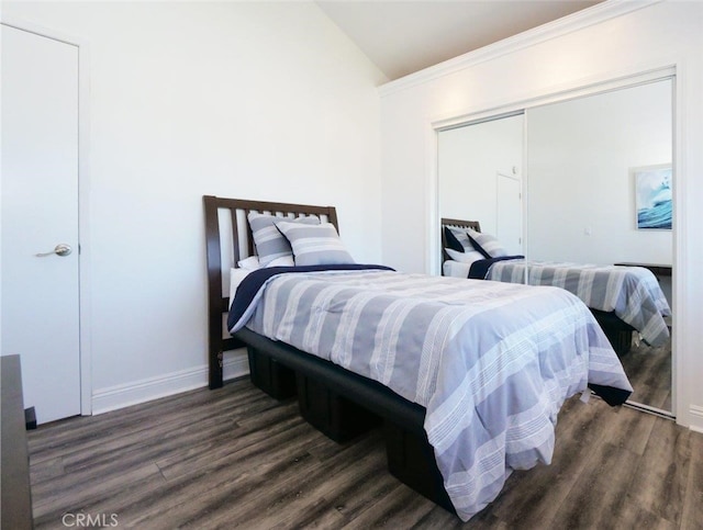 bedroom with dark hardwood / wood-style floors, a closet, and vaulted ceiling