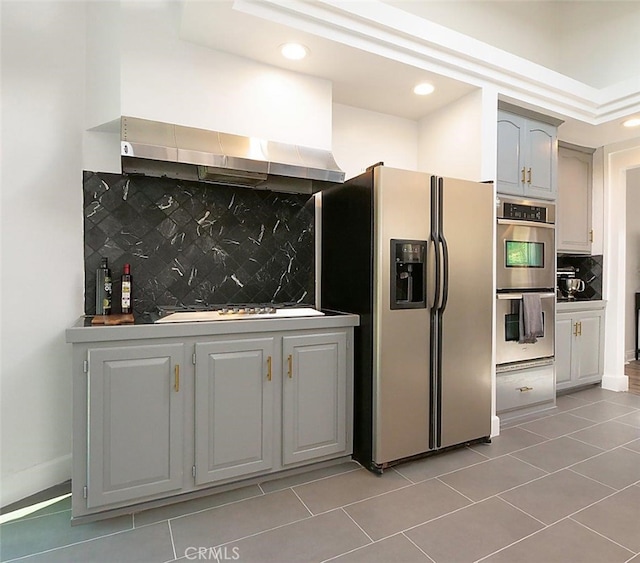 kitchen featuring appliances with stainless steel finishes, extractor fan, tile patterned flooring, backsplash, and gray cabinetry