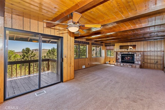 unfurnished living room featuring carpet floors, a fireplace, wooden walls, and ceiling fan