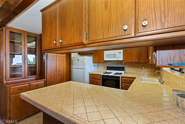 kitchen featuring white appliances, kitchen peninsula, tile countertops, and sink