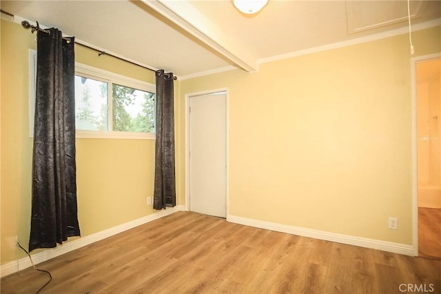 spare room with hardwood / wood-style floors, beamed ceiling, and ornamental molding