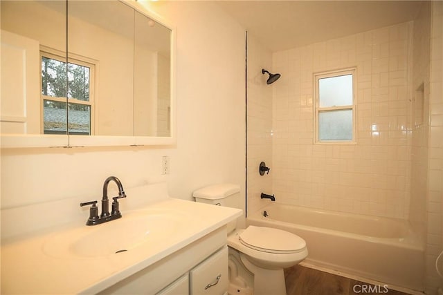 full bathroom featuring toilet, wood finished floors, vanity, and washtub / shower combination