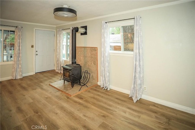 living room with a wood stove, wood-type flooring, and ornamental molding