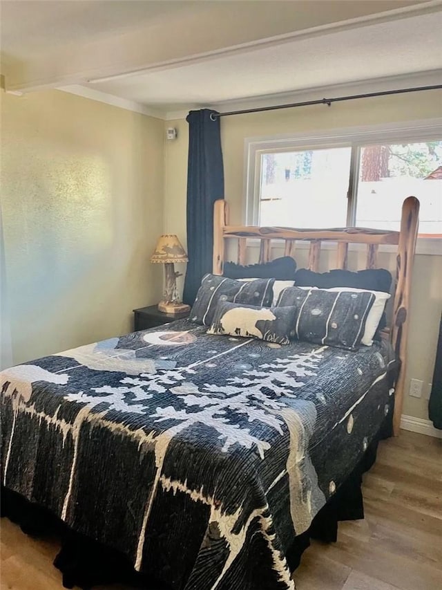 bedroom with beam ceiling and wood finished floors