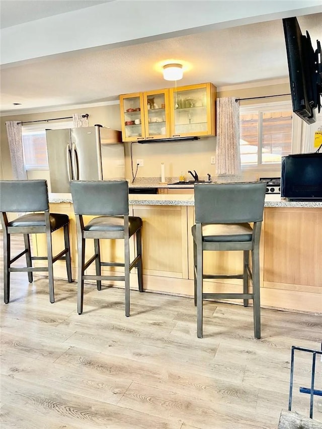 bar featuring freestanding refrigerator, a sink, and light wood-style flooring