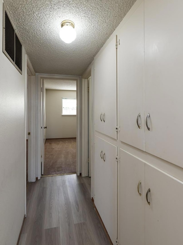 hall featuring a textured ceiling and light wood-type flooring