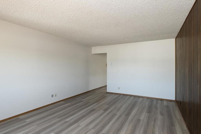 spare room featuring light hardwood / wood-style flooring, a textured ceiling, and wood walls