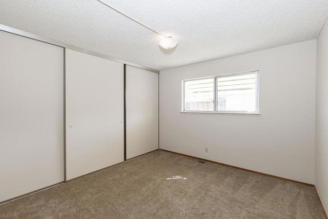 unfurnished bedroom featuring light colored carpet, a closet, and a textured ceiling