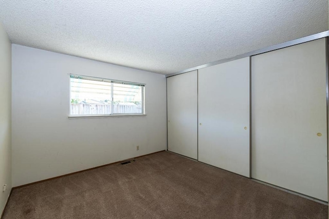 unfurnished bedroom featuring light colored carpet, a closet, and a textured ceiling