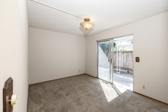 empty room with carpet floors and a textured ceiling