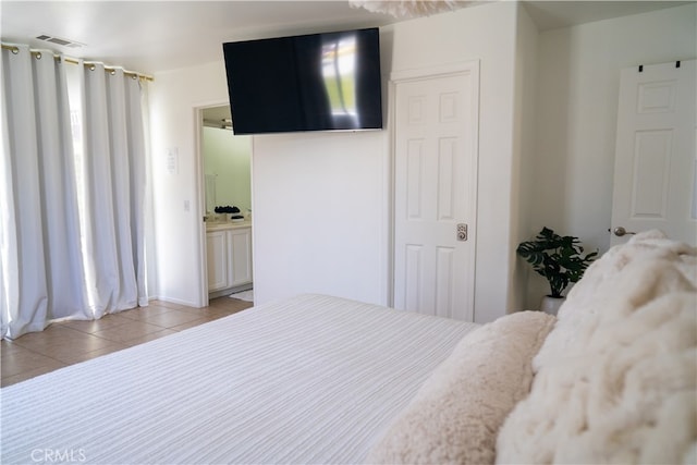 bedroom featuring ensuite bath and light tile patterned floors