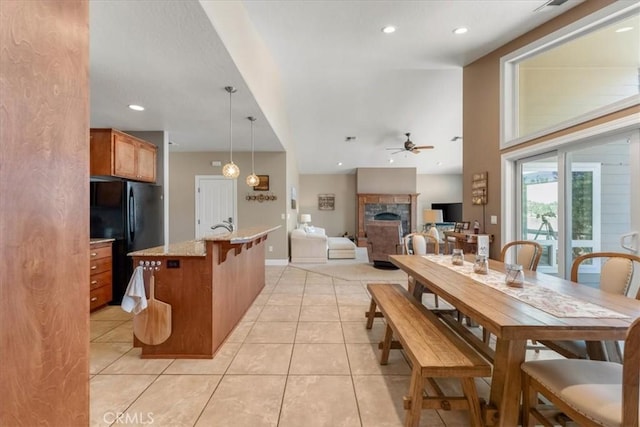 tiled dining area with a fireplace and ceiling fan