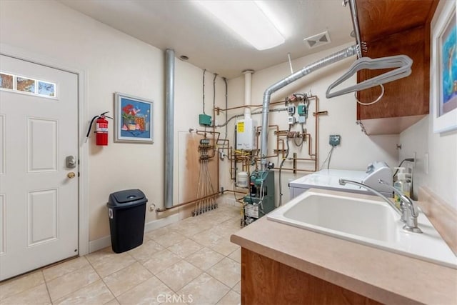 washroom with washer / clothes dryer, water heater, light tile patterned floors, and cabinets