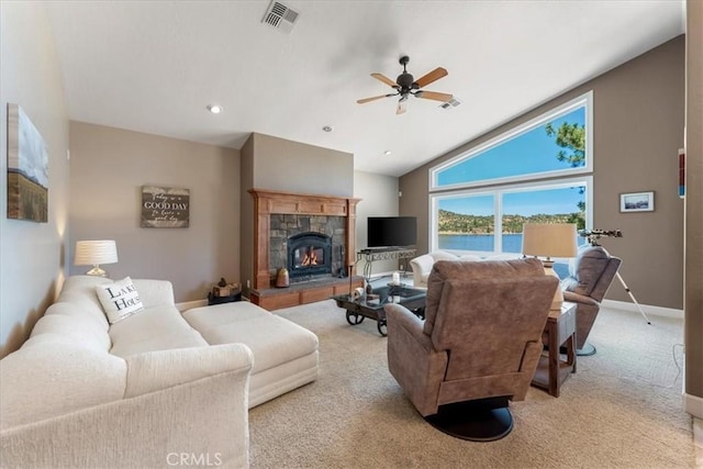 carpeted living room with a stone fireplace, ceiling fan, and lofted ceiling