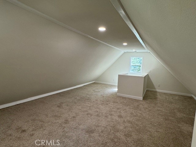 additional living space featuring carpet flooring and vaulted ceiling